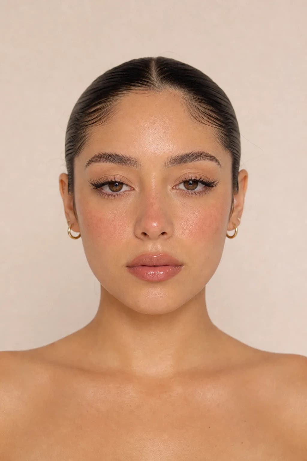 Model with fair olive skin wearing soft doe-eyed makeup, wispy lifted lashes and blush high on the cheek, head square to the camera
